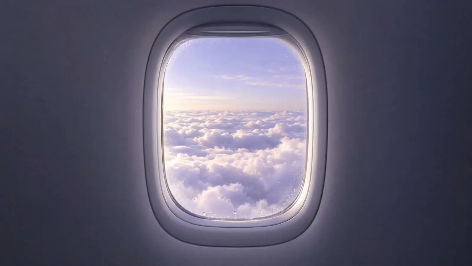 Looking out of an aircraft window at bright cloud tops in early morning light