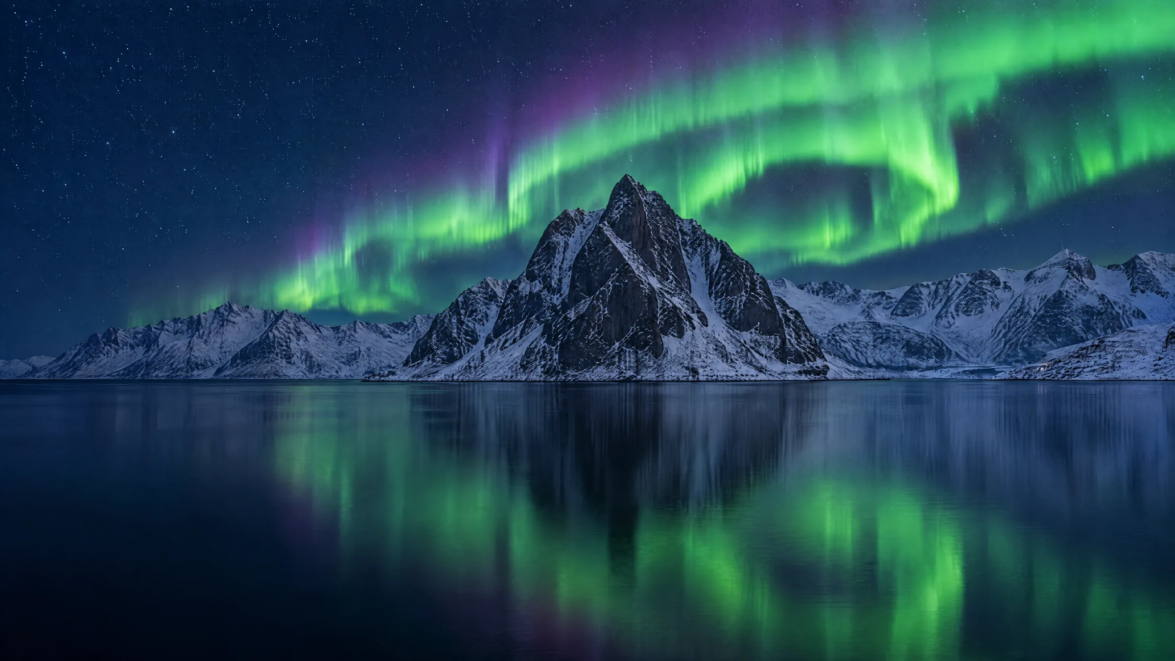Illustration of the northern lights above a snow-covered peak and fjord, with red fishing cabins on the shore